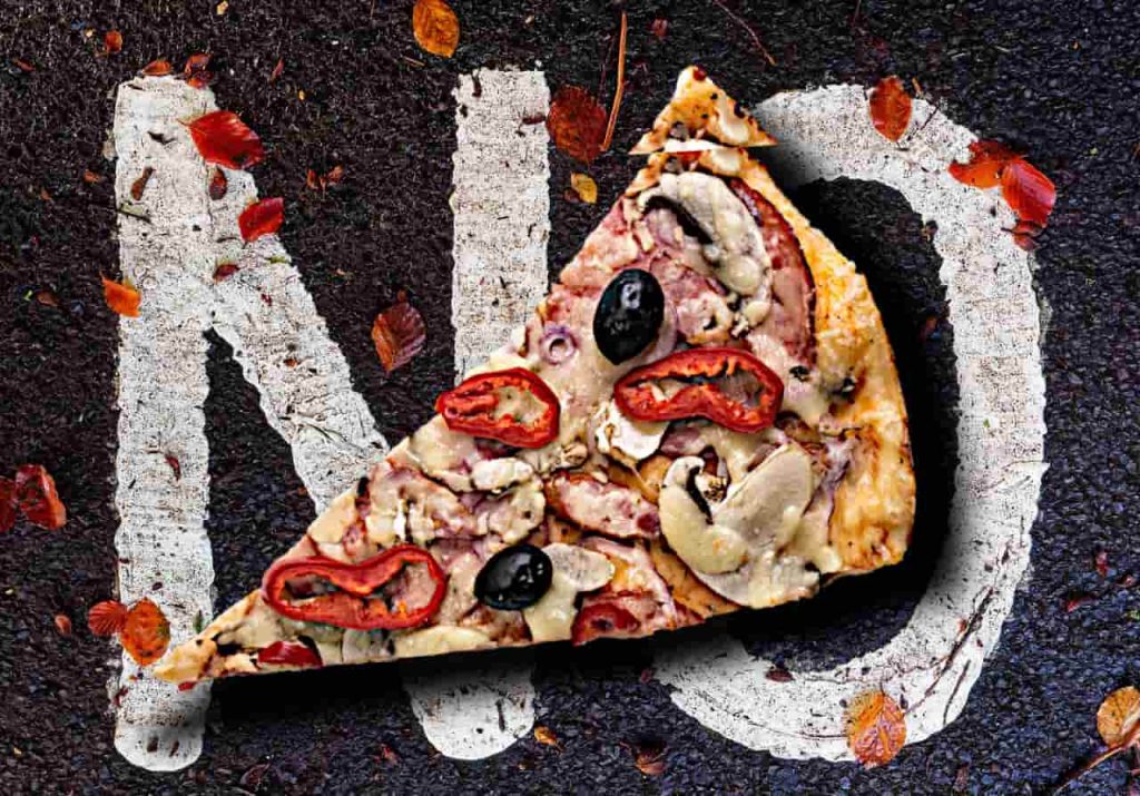 a slice of pizza lies on top of tarmac painted with the word NO
