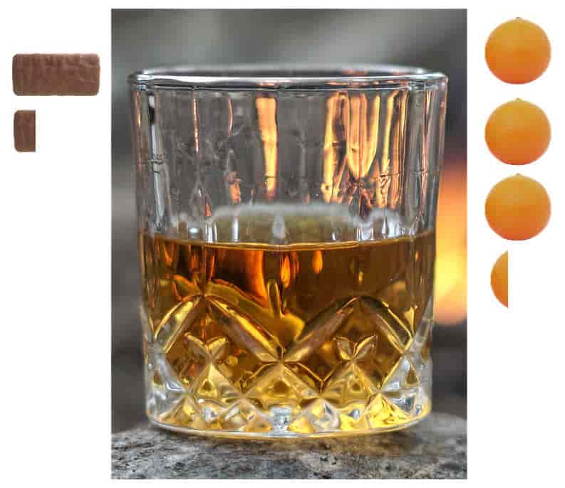 A crystal glass half- filled with whiskey is placed on a textured surface, with a warm, fire-lit background. There are 1.2 tim tam biscuits on the left of the glass; 3.2 oranges on the right.
