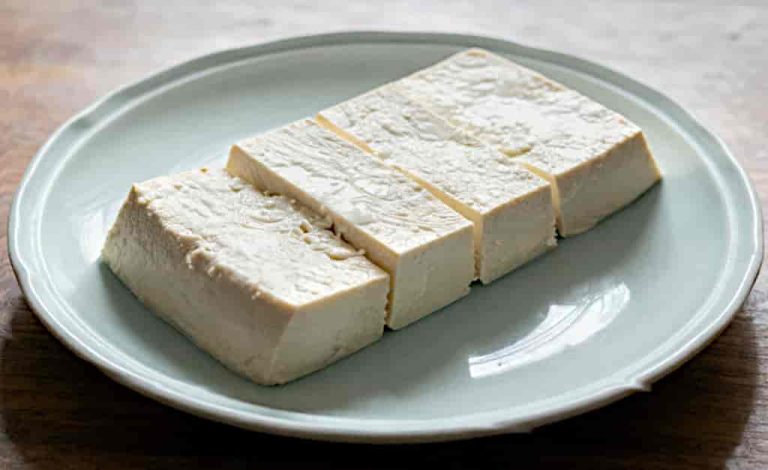 Thick rectangular slices of tofu on a pale green plate.